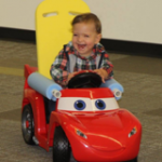 Toddler laughing and playing in a riding toy car adapted by Go Baby Go Seattle